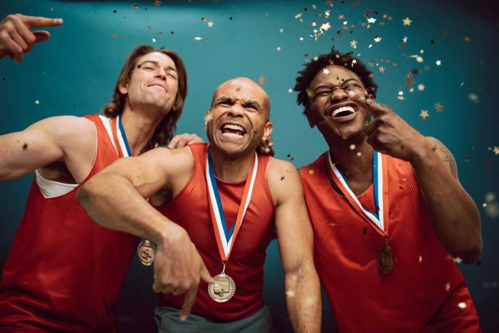 Three diverse athletes celebrate their victory with medals and confetti.