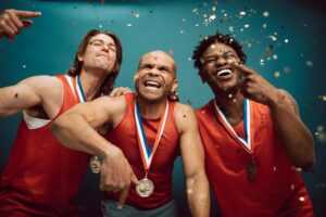Three diverse athletes celebrate their victory with medals and confetti.