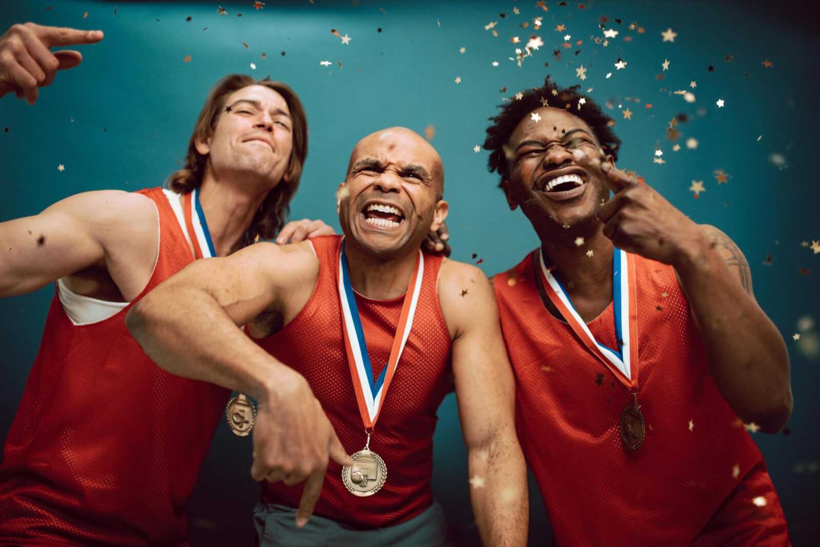Three diverse athletes celebrate their victory with medals and confetti.